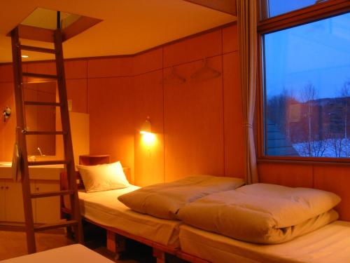 two beds in a room with a ladder and a window at Kussharo Genya Youth Guesthouse in Teshikaga