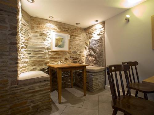 una sala da pranzo con tavolo e parete in pietra di The Anchor Inn a Ivybridge