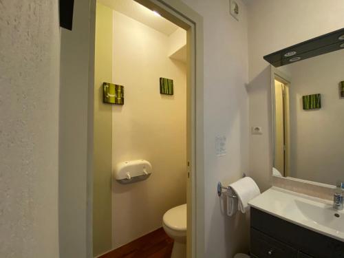 a bathroom with a sink and a toilet and a mirror at Hôtel Fontaine, Morlaix in Morlaix