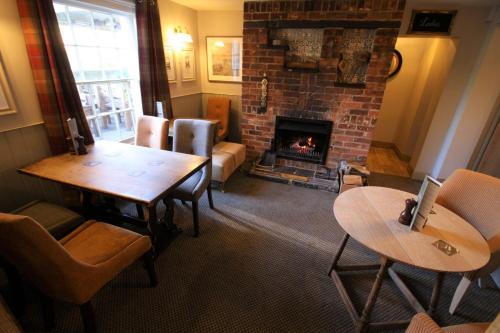 a living room with a fireplace and a table and chairs at The Carpenters Arms in Newbury
