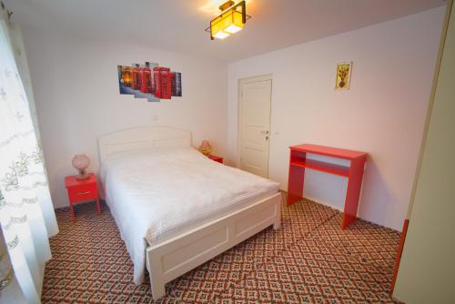 um quarto com uma cama branca e uma mesa vermelha em Casa Marica em Ceahlău