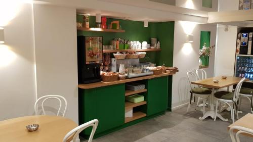 un restaurant avec des murs verts, des tables et des chaises dans l'établissement Hôtel Sunny, à Paris