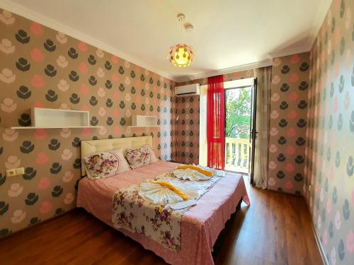 a bedroom with a bed with a pink blanket and a window at Sunrise Hotel in Kobuleti