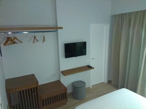 1 dormitorio con 1 cama y TV en la pared en Ariadni Rooms & Apartments, en Ermoupoli