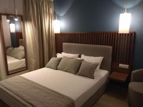 1 dormitorio con 1 cama grande y espejo en Ariadni Rooms & Apartments, en Ermoupoli