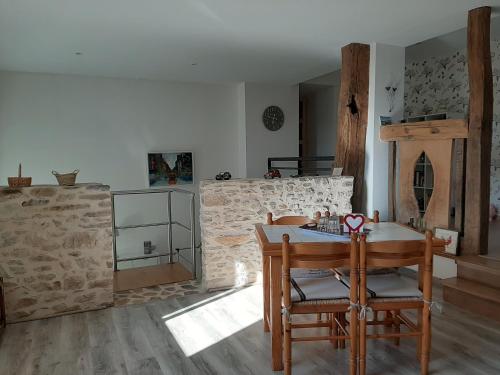 une cuisine avec une table et des chaises et un mur en pierre dans l'établissement Au Cœur de Mauchat, pour une escapade romantique, à Saint-Martin-de-Fressengeas