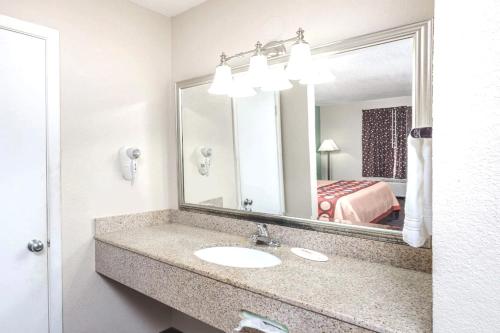 a bathroom with a sink and a mirror and a bed at Hotel 7 Inn Paducah in Paducah