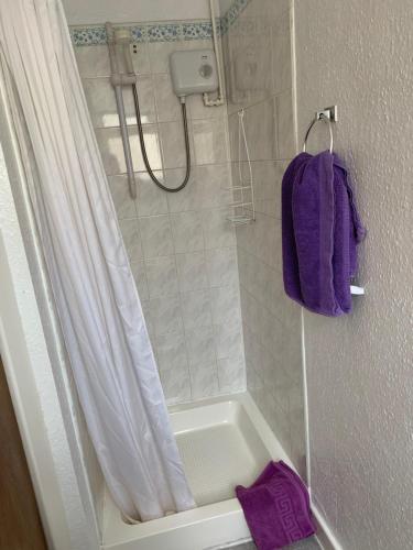 y baño con ducha y toalla púrpura. en Alondra Hotel, en Blackpool