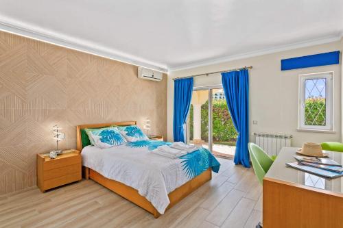 a bedroom with a bed with blue curtains and a desk at Vivenda Vista Mar in Carvoeiro