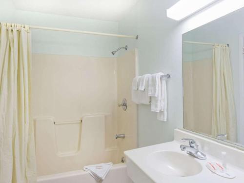 La salle de bains blanche est pourvue d'un lavabo et d'une douche. dans l'établissement POCONO NIGHT LODGE, à Bartonsville