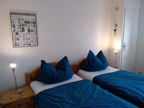 2 letti in una camera con cuscini blu sopra di Ferien bei Naus - Ferienwohnung a Marburg an der Lahn