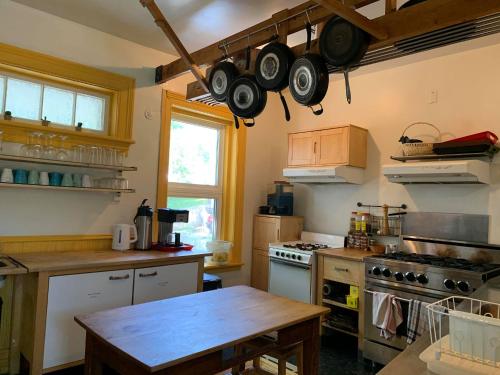 a kitchen with a table and some pots and pans hanging from the ceiling at Auberge Internationale de Rivière-du-Loup in Rivière-du-Loup