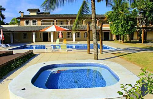 a large swimming pool in front of a house at Pousada Porto do Rio in Caraguatatuba