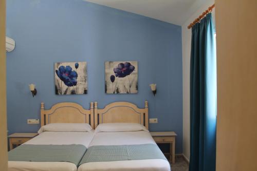 a bedroom with two beds and two paintings on the wall at Villa Elisabet in Cala en Forcat