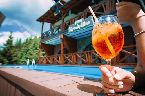 a person holding a drink on a table next to a pool at Chalet CrepDeChine Hotel in Bukovel