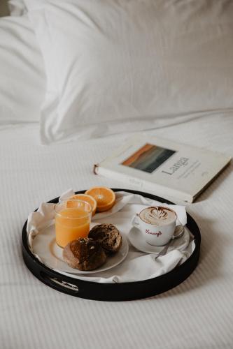 a tray of food with orange juice and donuts on a bed at Vincafè in Alba