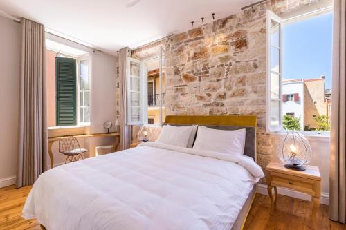 a bedroom with a large bed and a brick wall at Acanthus blue in Corfu