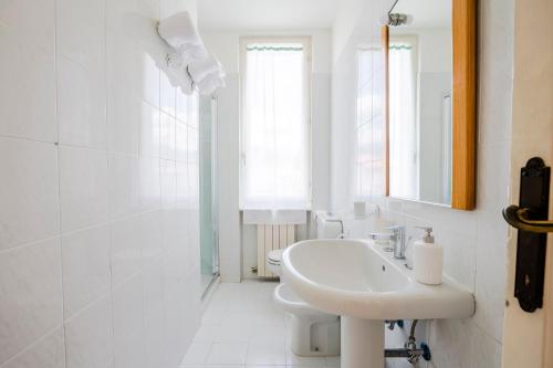 a white bathroom with a sink and a mirror at Forte 1013 in Forte dei Marmi
