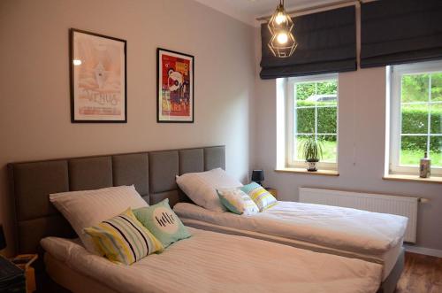 a bedroom with two beds and two windows at Apartament Fabryka Endorfin Kłodzko in Kłodzko