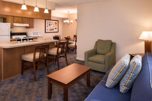 a living room with a couch and a kitchen at Charwood Suites in Columbus