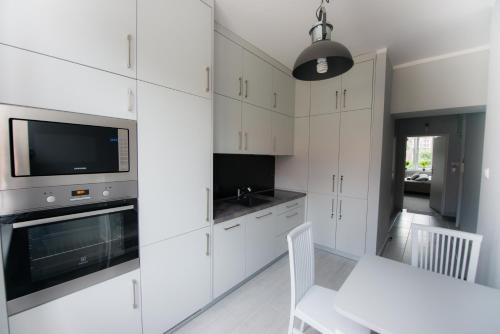 a kitchen with white cabinets and a table and a tv at Wide Street in Gdańsk