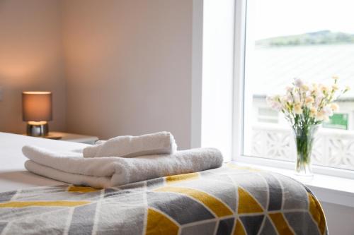 a bedroom with a bed with a vase of flowers in a window at Fairhaven, Oban Town Centre in Oban