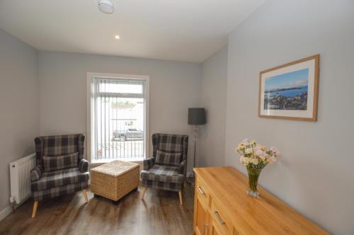 a living room with two chairs and a vase of flowers at Fairhaven, Oban Town Centre in Oban