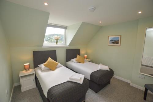 2 camas en una habitación pequeña con ventana en Fairhaven, Oban Town Centre, en Oban