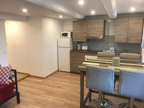 une cuisine avec une table, des chaises et un réfrigérateur dans l'établissement Appartement lac et montagne, à Saint-André-les-Alpes