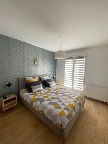 - une chambre avec un lit et une couette jaune et gris dans l'établissement Le Jardin Minelle, à Arras