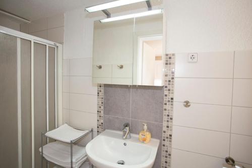 een witte badkamer met een wastafel en een spiegel bij Ferienwohnungen Beyer in Binz