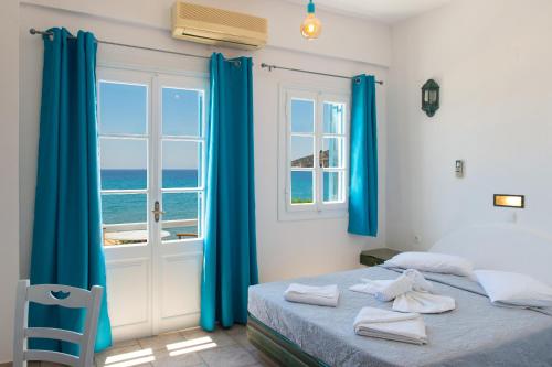 a bedroom with blue curtains and a bed and a window at Almyra Seaside Suites in Platis Gialos
