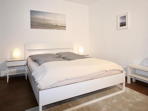 ein weißes Bett in einem weißen Schlafzimmer mit zwei Lampen in der Unterkunft Apartmenthaus in der Arnoldstraße in Bochum