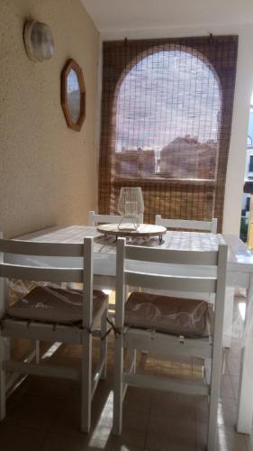une table et des chaises dans une pièce avec une fenêtre dans l'établissement Appartement Cosy sur la Presqu'île de Cap Coudalere avec terrasse, piscines, aire de jeux d'enfants, parking, commerces et animations, au Barcarès