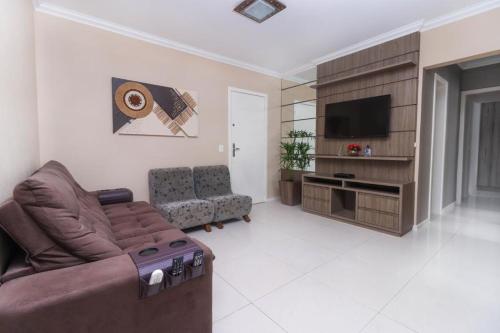 uma sala de estar com um sofá e uma televisão em APARTAMENTO VISTA MAR - Pé na areia em Balneário Camboriú