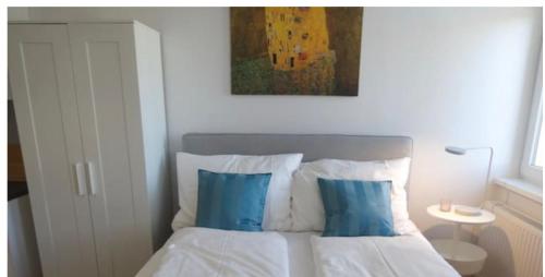a bedroom with a bed with blue pillows and a painting at Between Schoenbrunn and the City Center. Apt. 31 in Vienna