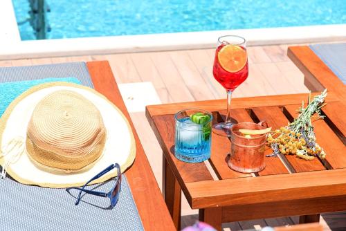 Acrothea Villa Heated Pool في مدينة خانيا: طاولة مع قبعة من القش وكأس من النبيذ