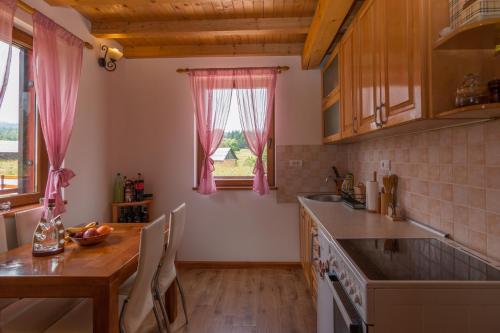a kitchen with a wooden table and a dining room at Planinska kuca Popovic 3 in Ljuboš