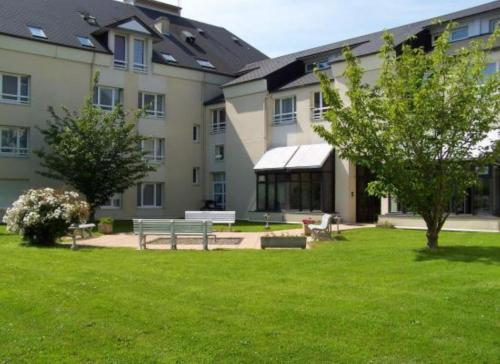 un bâtiment avec un banc dans l'herbe dans l'établissement Sphinx Résidences - Les Doges / Le Rialto, à Caen