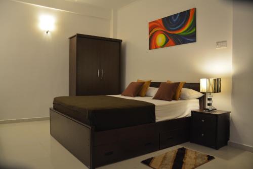 een slaapkamer met een bed met een kast en een lamp bij Panoramic Holiday Apartment - Luxury Studio | Nuwara Eliya in Nuwara Eliya