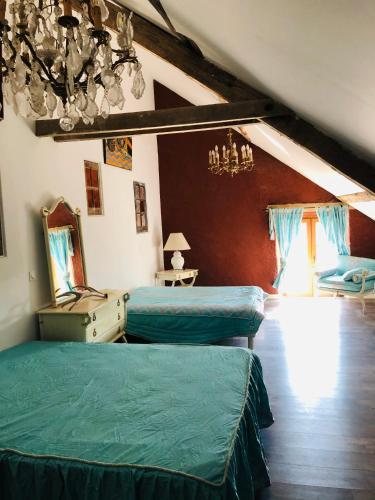une chambre avec deux lits, un miroir et un lustre dans l'établissement Chambre familiale Élevage Girbal, à La Chapelotte