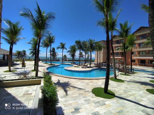 a resort with a swimming pool and palm trees at Manacá Apartamentos , Kariri Beach , Cumbuco in Cumbuco