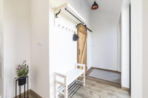 a white hallway with a wooden door and a bench at Babyky apartmány in Jindrichuv Hradec