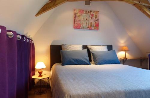een slaapkamer met een groot bed met blauwe kussens bij Pergoloire in La Bohalle