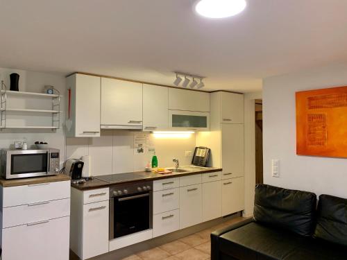 グリンデルワルトにあるAmazing Apartment EIGER Grindelwaldの白いキャビネットとソファ付きのキッチンが備わります。