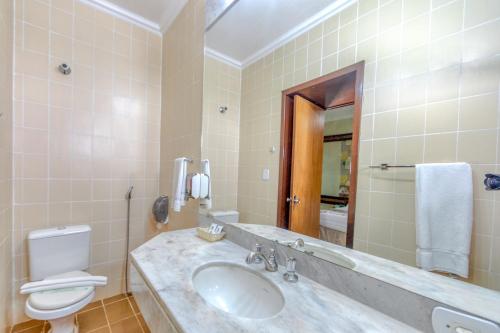 een badkamer met een wastafel, een toilet en een spiegel bij Hotel Colonial Iguaçu in Foz do Iguaçu