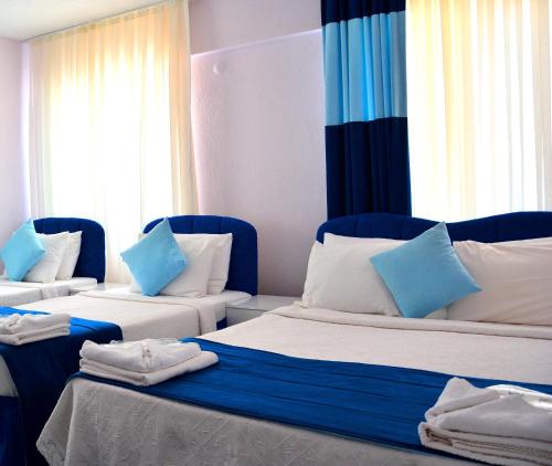 a room with two beds with blue and white pillows at Gumuldur Mavi Deniz Hotel in Gumuldur