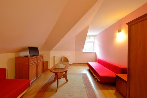 a living room with a red couch and a table at Zajazd u Hermanów in Olsztyn