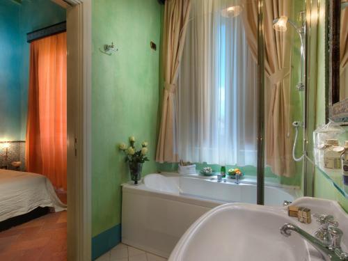 a bathroom with a tub, sink and mirror at Graziella Patio Hotel in Arezzo