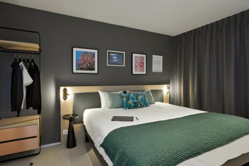 a bedroom with a large bed with a green blanket at Aparthotel & Spa Adagio Vannes in Vannes